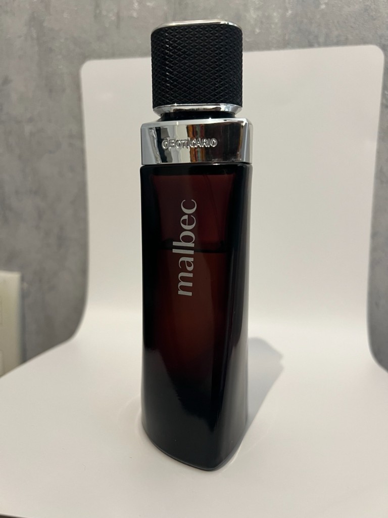 Produto Malbec em estúdio: frasco centrado, superfície clara e fundo neutro