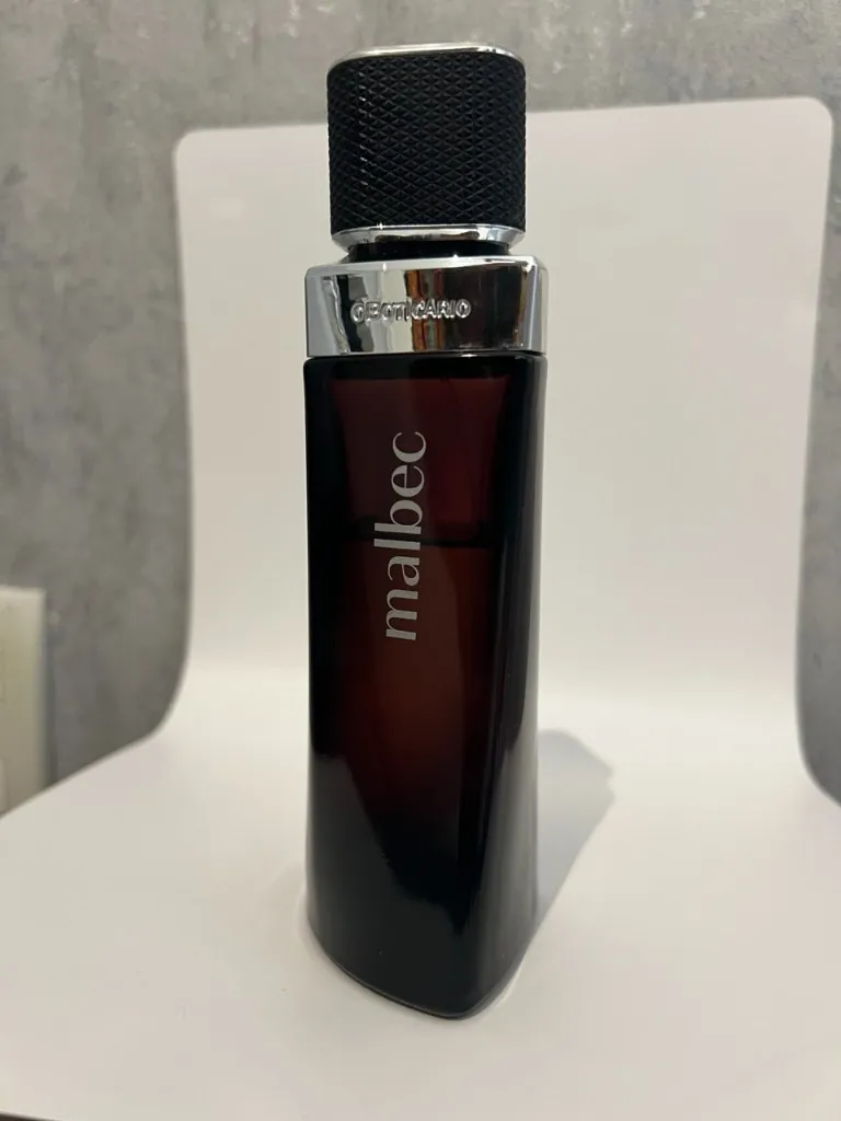 Produto Malbec em estúdio: frasco centrado, superfície clara e fundo neutro